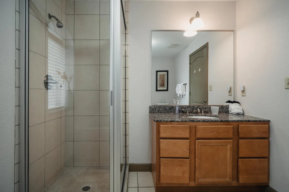 A bright bathroom with a modern glass shower, granite countertop, and mirror reflection. The space feels fresh and spa-like, ideal for daily routines or unwinding after an adventure.